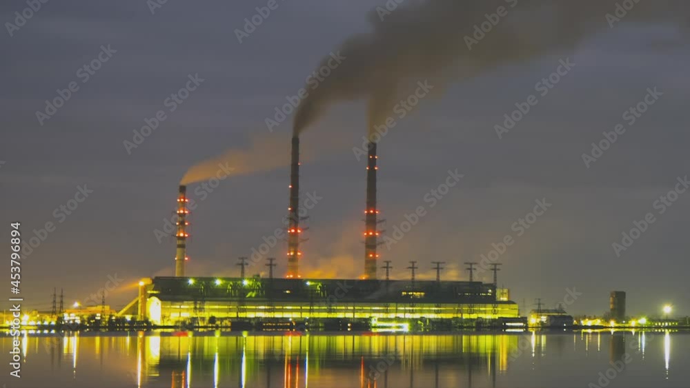 Time lapse of coal power plant high pipes with black smoke moving fast polluting atmosphere at night with reflections of it in lake water. Time lapse of coal power plant high pipes with black smoke moving fast polluting atmosphere at night with reflections of it in lake water.