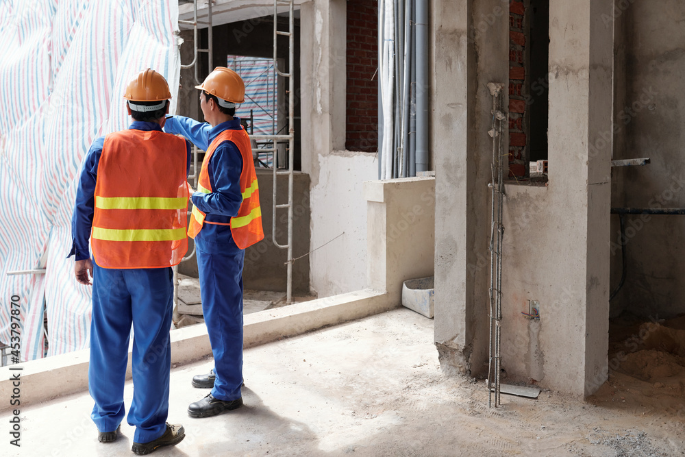 Head contractor showing site to construction manager and explaining what changes his team is going to make Head contractor showing site to construction manager and explaining what changes his team is going to make