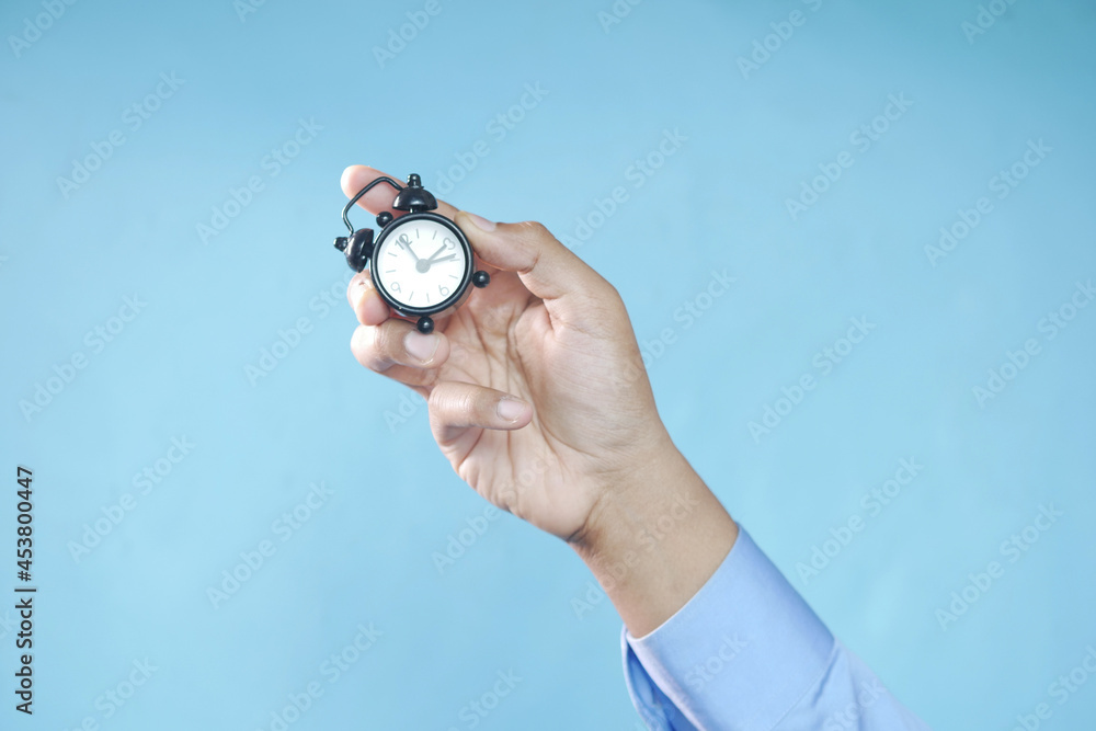 person hand holding alarm clock against blue background , person hand holding alarm clock against blue background ,