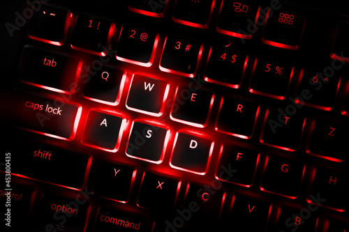 Red color backlighted computer keyboard. Close-up of highlighted default keys in games associated with movements. photo