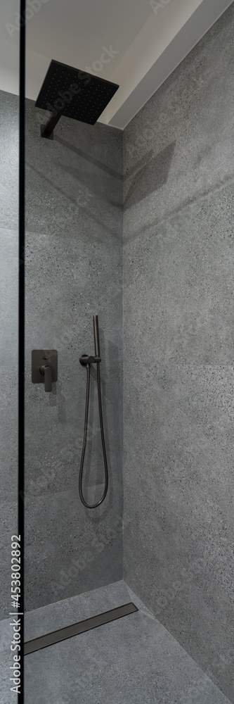 Shower with glass wall and granite tiles, vertical panorama