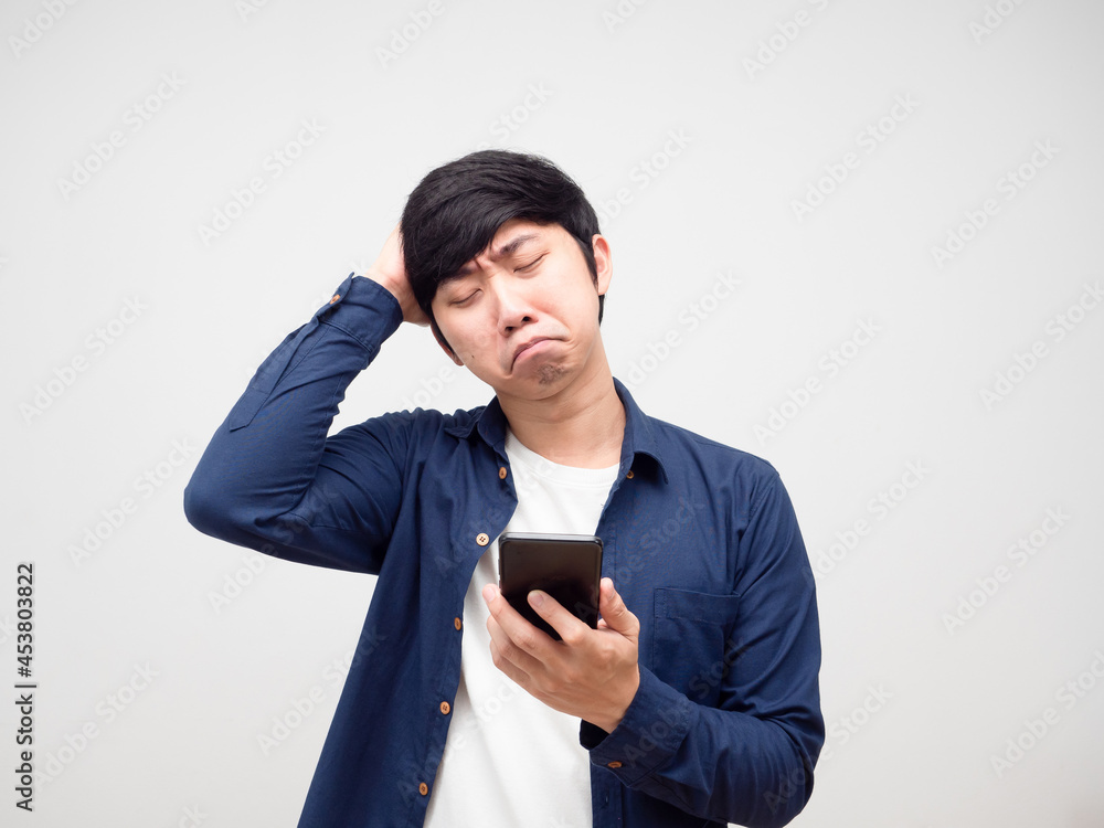 Young man feeling sad holding mobile phone in hand portrait white isolated Young man feeling sad holding mobile phone in hand portrait white isolated