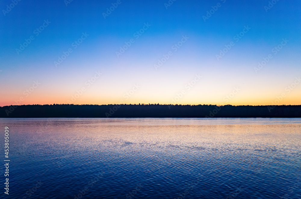 Tranquil minimalist landscape with a smooth lake surface with calm waters with a horizon and clear skies. Simple beautiful natural calm background. Copy space