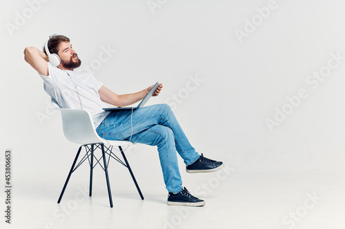 bearded man sitting on a chair with a laptop in headphones entertainment