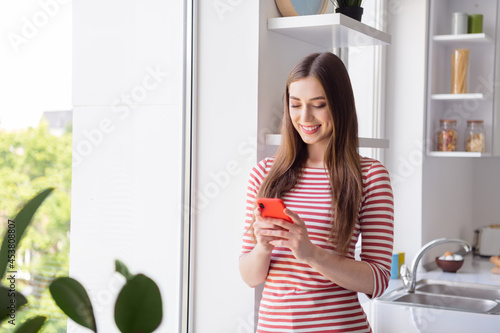 Photo of pretty young nice woman good mood hold phone rest relax smile weekend indoors inside kitchen