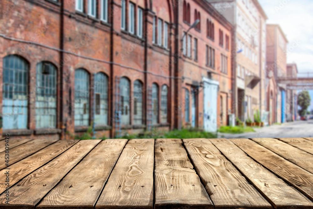 A wooden table surrounded by old factories with a free space 
