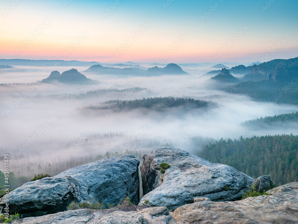 Kleiner Winterberg, beautiful morning view over sandstone cliff into deep misty valley in Saxony Switzerland, landscape Germany. Fog and beautiful backlight.