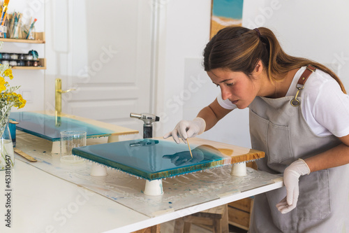 A young woman creates a painting using liquid art technique. The process of resin art. photo