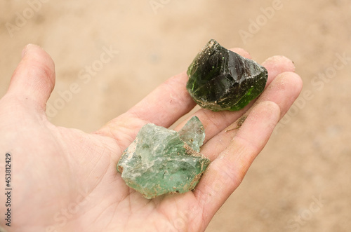 Human palm and found pieces of green glass. Remains of a former glass factory. photo