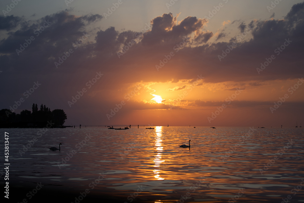 Beautiful sunset on a summer evening seen from border of lake Bodensee at City of Bregenz. Photo taken August 15th, 2021, Bregenz, Austria. Beautiful sunset on a summer evening seen from border of lake Bodensee at City of Bregenz. Photo taken August 15th, 2021, Bregenz, Austria.