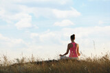 Woman meditating in meadow, back view. Space for text