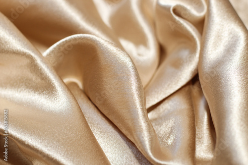 Shiny golden textured silk background in folds.