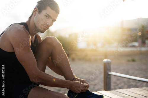 Sporty athletic man exercises at the beach. Handsome man training outdoors..