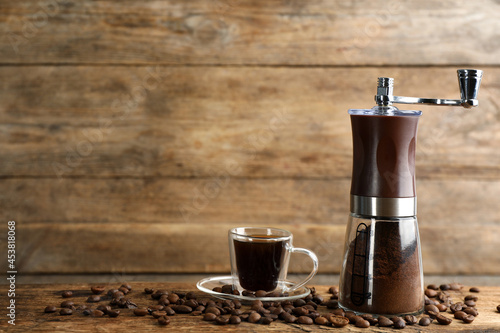 Bild auf Leinwand Manual coffee grinder with powder, beans and cup of drink on wooden table