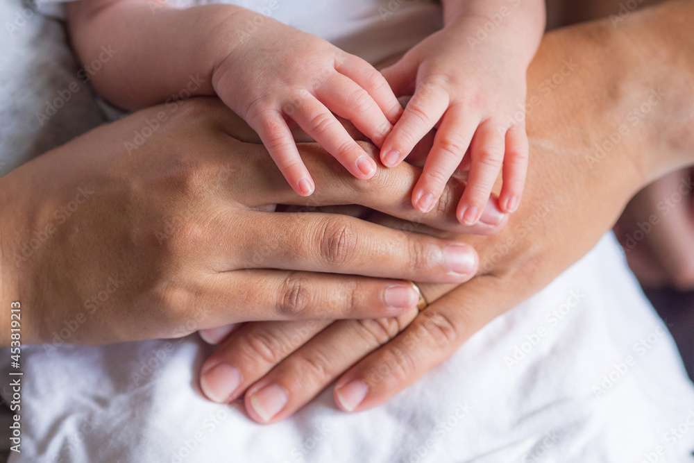 Close-up of newborn hands placed on mother and father hands on white cloth. Happiness parents. Love of family concept. Space for text Close-up of newborn hands placed on mother and father hands on white cloth. Happiness parents. Love of family concept. Space for text