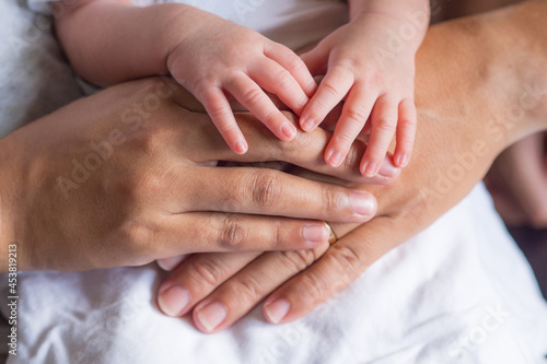 Close-up of newborn hands placed on mother and father hands on white cloth. Happiness parents. Love of family concept. Space for text © meeboonstudio