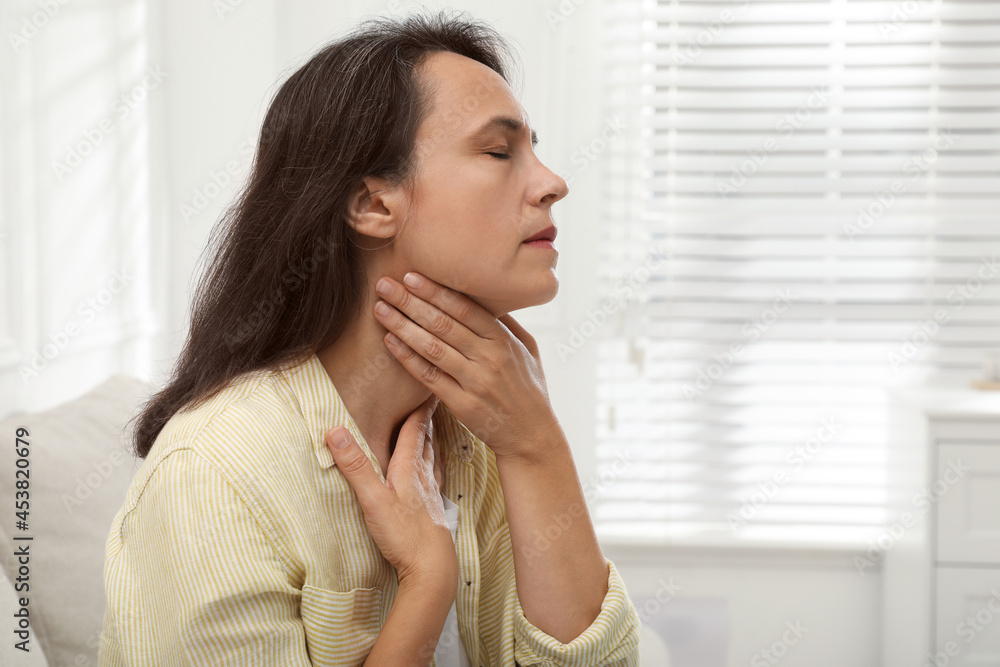 Mature woman doing thyroid self examination at home. Space for text Mature woman doing thyroid self examination at home. Space for text