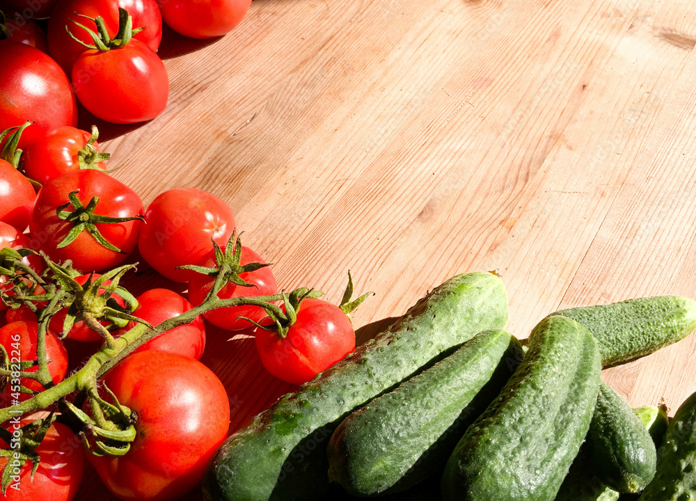 Red tomatoes and green cucumbers on a wooden background.Fresh vegetables top view with copy space for text. Flat lay. The concept of the harvest, vegetable garden.Natural products, agriculture. Layout Red tomatoes and green cucumbers on a wooden background.Fresh vegetables top view with copy space for text. Flat lay. The concept of the harvest, vegetable garden.Natural products, agriculture. Layout