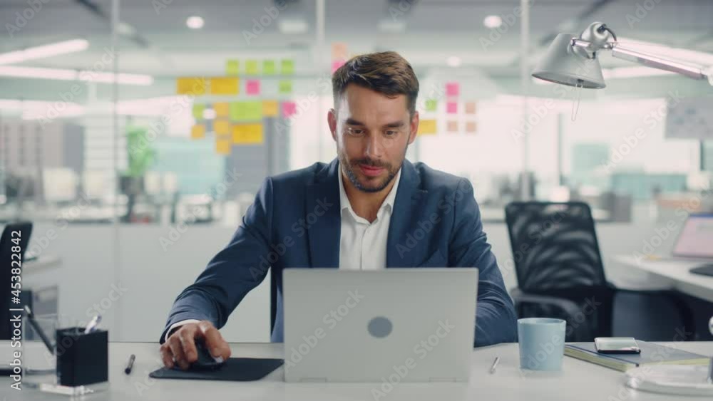 Young Happy Businessman Using Computer in Modern Office with Colleagues. Successful Handsome Manager Smiling, Working on Financial and Marketing Projects. Drinking Tea or Coffee from a Mug. Young Happy Businessman Using Computer in Modern Office with Colleagues. Successful Handsome Manager Smiling, Working on Financial and Marketing Projects. Drinking Tea or Coffee from a Mug.