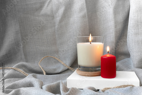 burning candles standing on a white paper on a gray fabric background