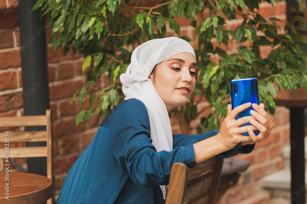 Muslim woman taking selfie. Happy beautiful girl with scarf take picture of her self using smartphone. Muslim woman taking selfie. Happy beautiful girl with scarf take picture of her self using smartphone.