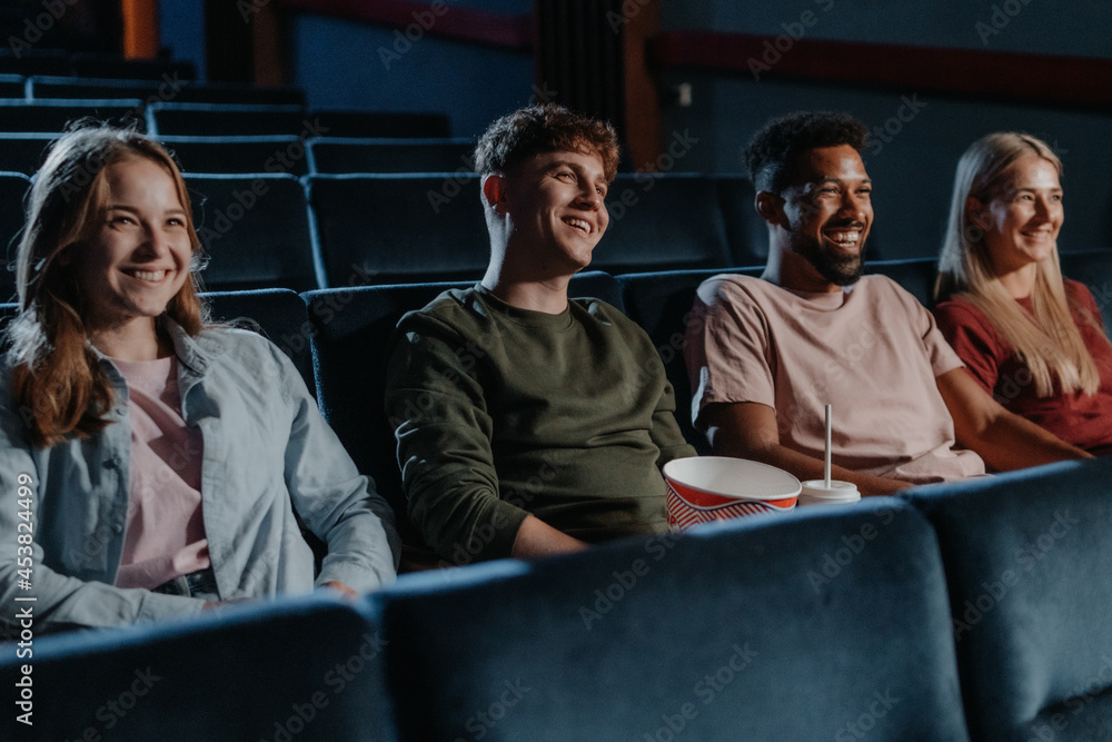 Obraz premium Young people with popcorn in the cinema, watching thriller film.