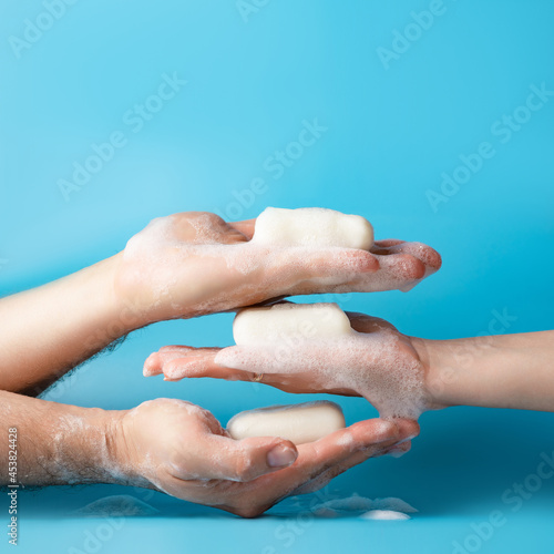 Global Handwashing Day, personal hygiene concept. Three hands in soapy foam with soap on a blue background on a light blue background.