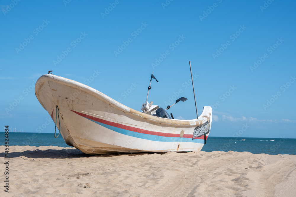 Striped boats docked on the beach, blue sky, sea and beach