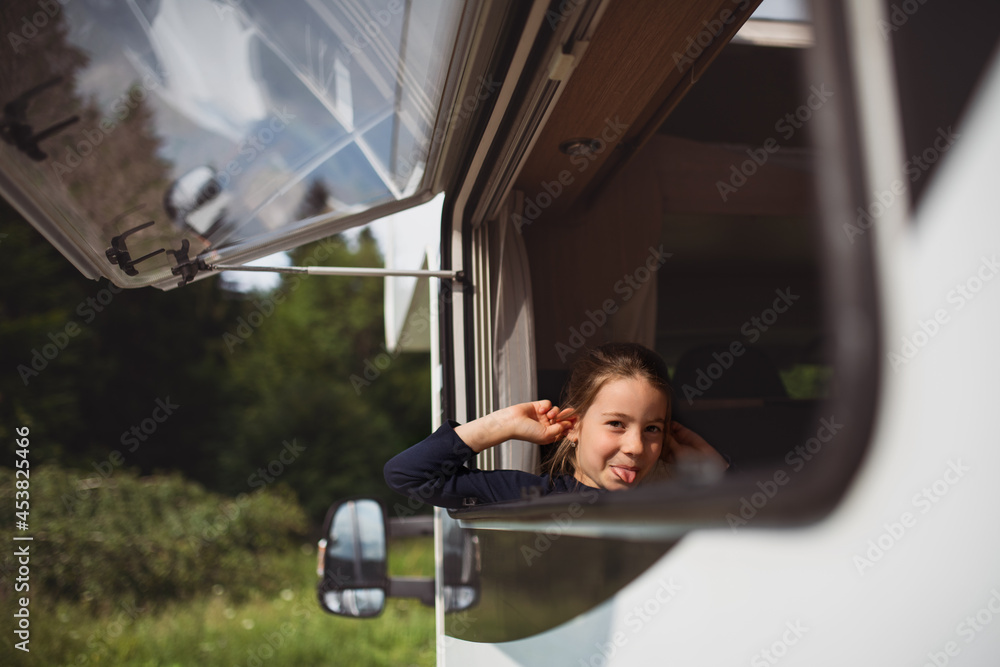 Small girl looking out through caravan window and making faces, family holiday trip. Small girl looking out through caravan window and making faces, family holiday trip.