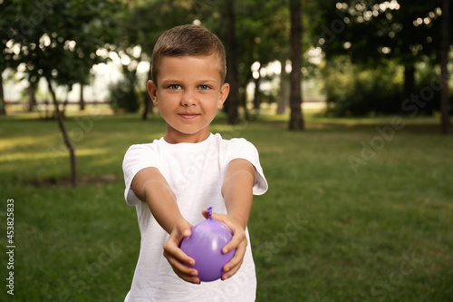 Cute little boy holding water bomb in park