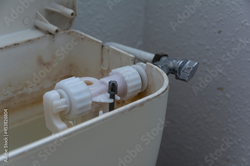 An old broken toilet flush with a plastic tank opened