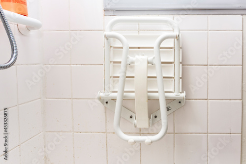 A white folded chair for disabled people in a shower