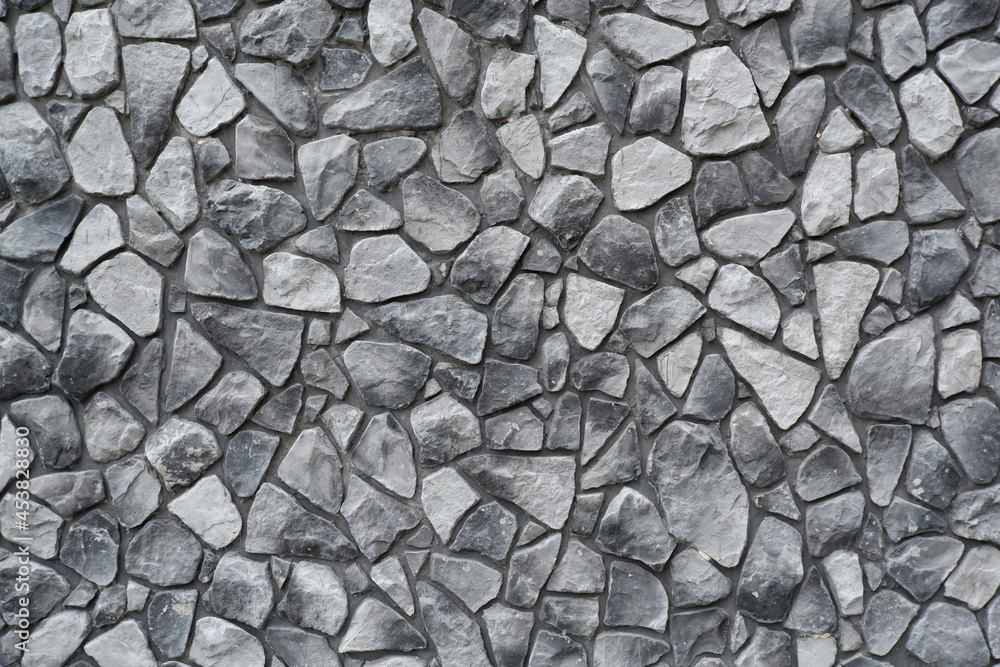 Black and white background of a stone wall.The walls are made by hand from concrete and stone, as the decor of a modern building.Background of an ancient stone wall. Black and white background of a stone wall.The walls are made by hand from concrete and stone, as the decor of a modern building.Background of an ancient stone wall.