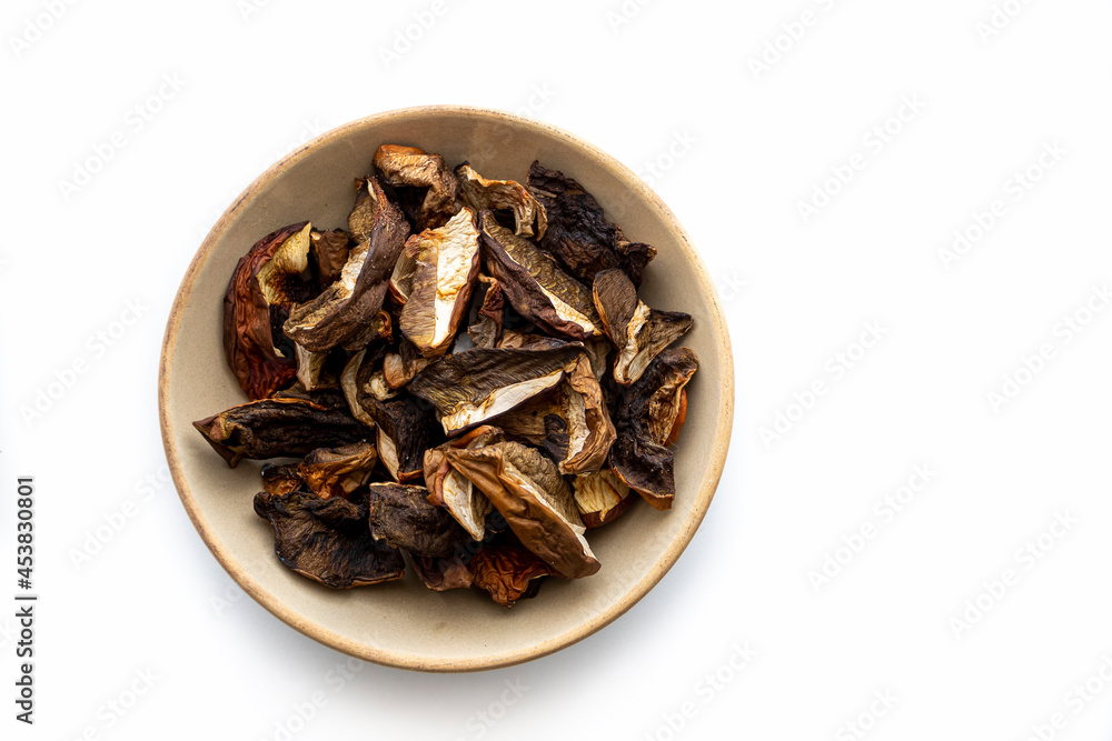 Closeup of dried mushrooms. Sliced boletus edulis in a light brown ceramic bowl isolated on white background. Selective focus on the food, blurred background. Closeup of dried mushrooms. Sliced boletus edulis in a light brown ceramic bowl isolated on white background. Selective focus on the food, blurred background.