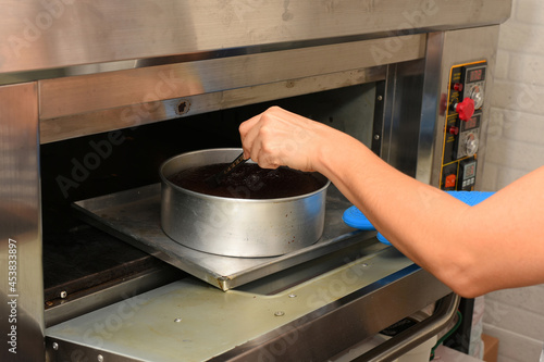 close up of hands taking out chocolate cake from hot oven