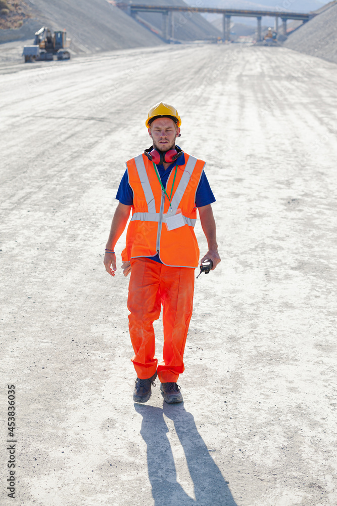 Fototapeta premium Worker smiling by machinery in quarry