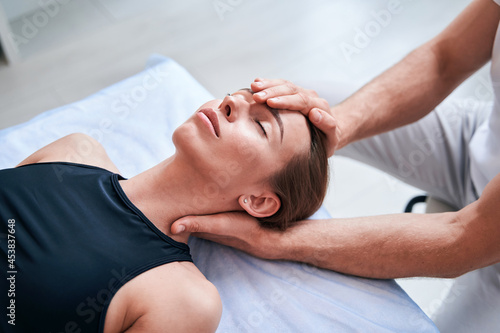 Canvas Print Unrecognized male physiotherapist working with attractive woman in medical offic