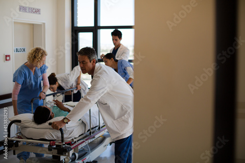 Doctors rushing patient on gurney in hospital corridor