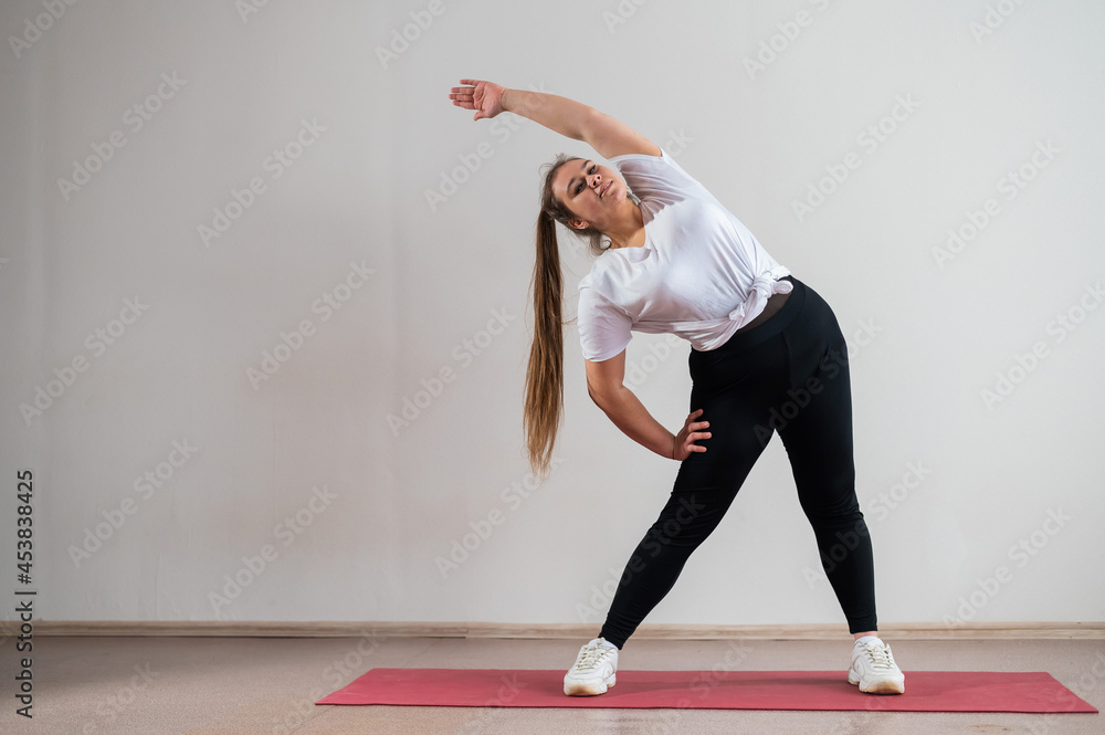 Naklejka premium Young fat woman doing flexibility exercises on a white background