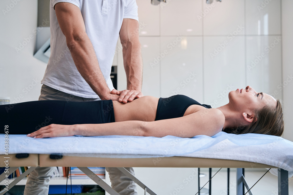 Beautiful elegant female on massage table getting massage therapy in medical office Beautiful elegant female on massage table getting massage therapy in medical office