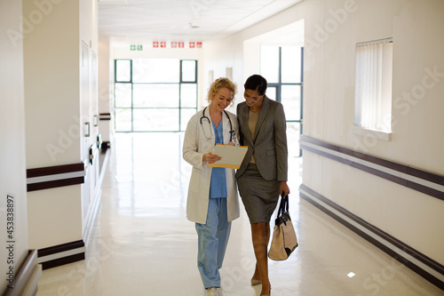 Doctor and businesswoman walking in hospital corridor