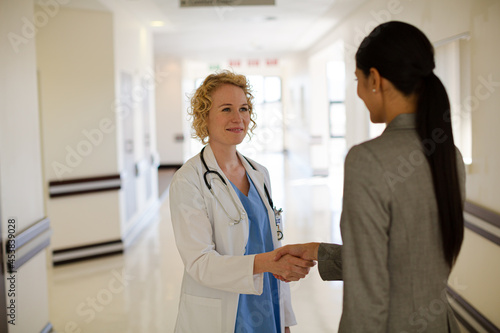 Doctor and businesswoman handshaking in hospital corridor © KOTO