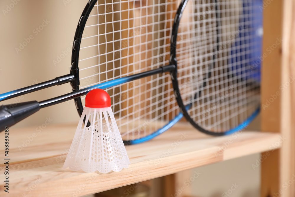 Badminton rackets and shuttlecock on wooden shelf, closeup