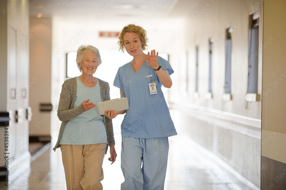 Obraz premium Nurse and senior patient talking in hospital corridor