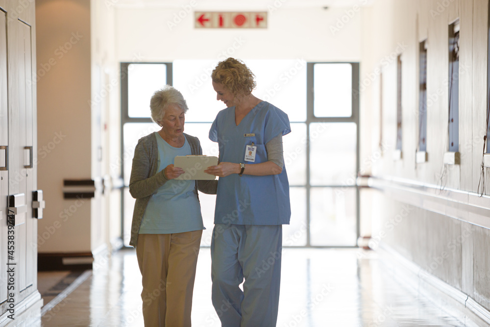 Nurse and aging patient reading chart in hospital corridor Nurse and aging patient reading chart in hospital corridor