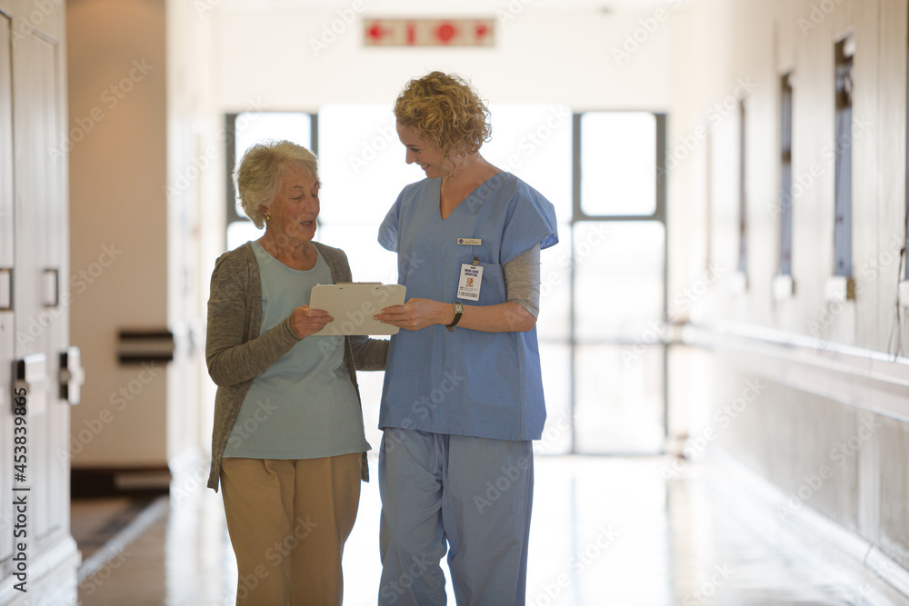 Nurse and aging patient reading chart in hospital corridor Nurse and aging patient reading chart in hospital corridor