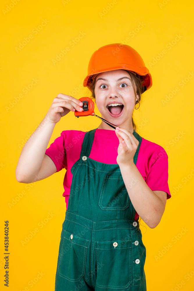 cheerful child laborer using building uniform and tape measure tool, sizing cheerful child laborer using building uniform and tape measure tool, sizing