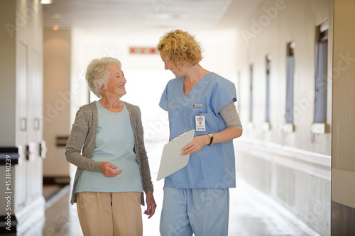 Nurse and senior patient talking in hospital corridor