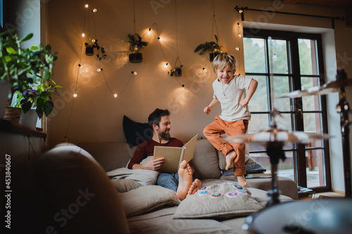 Mature father with small son resting indoors at home, looking at photo album.