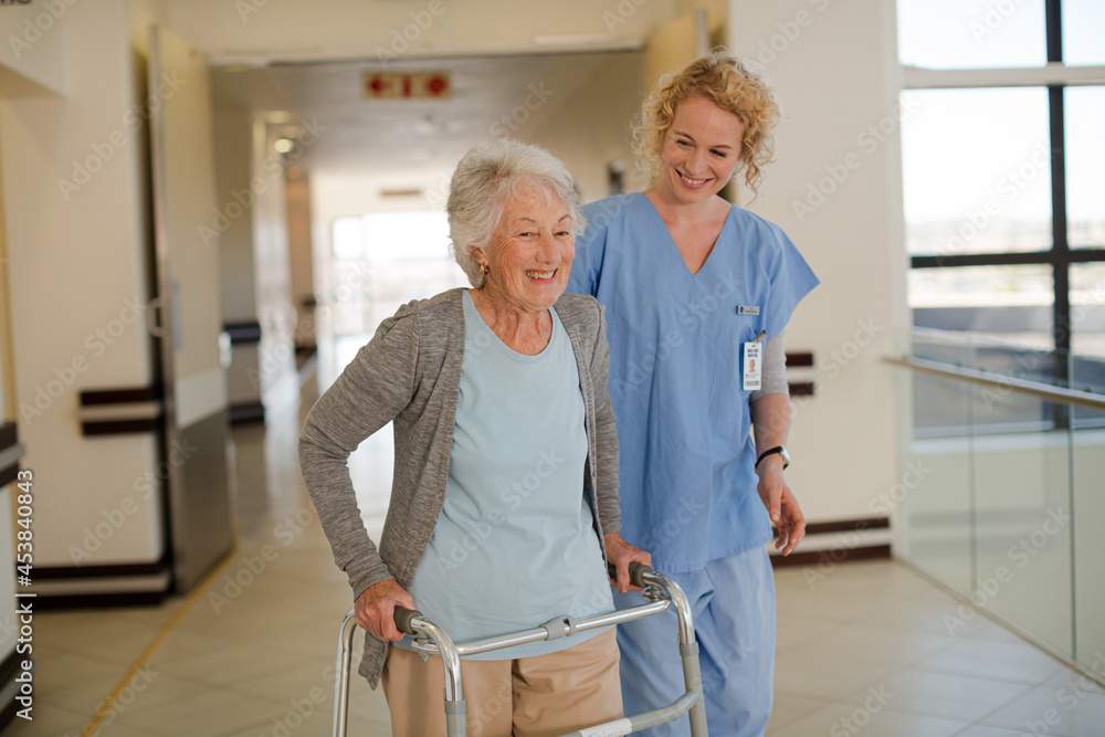 Nurse helping senior patient with walker in hospital corridor Nurse helping senior patient with walker in hospital corridor
